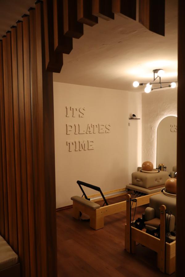 Sala del estudio vista entre los listones de madera, con el muro en relieve al fondo