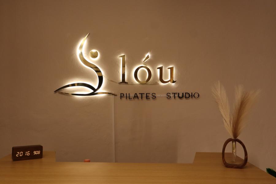 Detalle del logo de lóu Pilates Studio iluminado en el muro